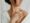 Woman applying moisturizer to her shoulder, showcasing smooth, healthy skin while wrapped in a cozy bathrobe.