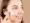 Smiling young woman applying acne cream on her cheek to treat pimples and skin redness