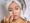 Woman applying facial cream with a towel wrapped around her head skincare routine for healthy and glowing skin